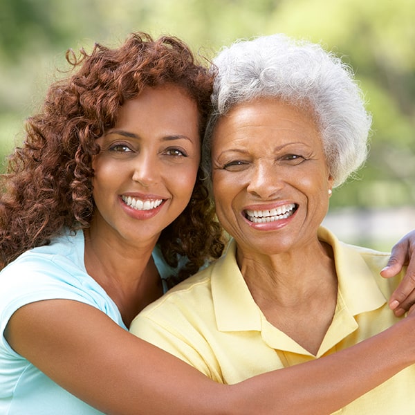 A teenage girl hugging her grandmother in the park 