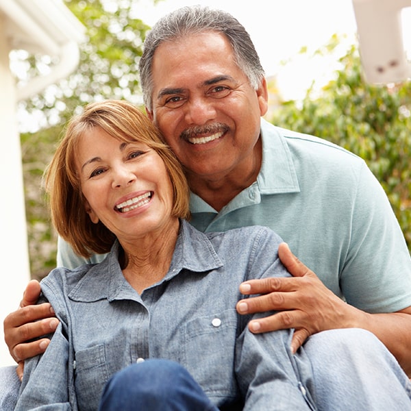 An older couple smiling as they hug