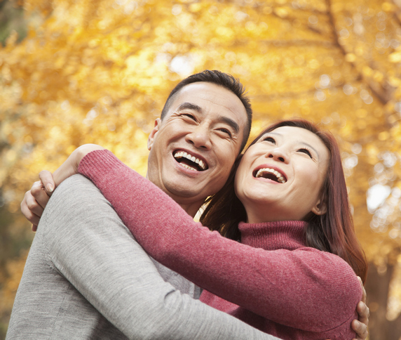 An adult couple smiling in the fall